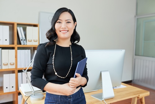 Pretty successful business lady with tablet computer standing in office Professional learning French in a business course